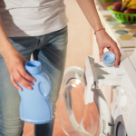 Woman using washing conditioner in washing machine